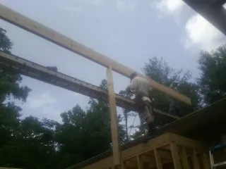 Carpenter setting a ridge beam over a new addition frame — Ice Dam Removal by Roofing Brothers in Worcester
